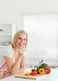 Portrait of a blonde woman eating red peppers