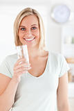 Smiling woman holding glass of water looks into camera