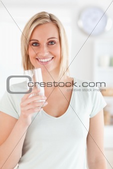Smiling woman holding glass of water looks into camera