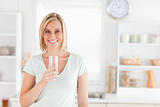 Charming woman holding glass filled with water while standing 