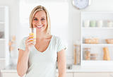 Charming woman holding glass filled with orange juice 
