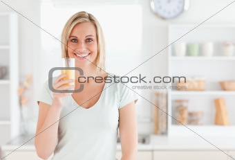 Charming woman holding glass filled with orange juice 