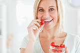 Close up of a woman eating strawberries looking into the camera 