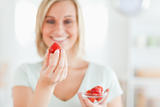 Close up of a young woman enjoying eating strawberries 