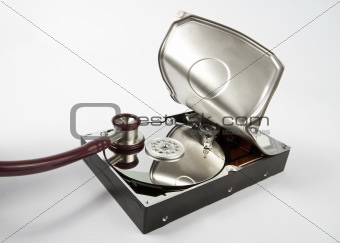 opened hard disk with stethoscope on grey background