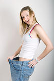 Happy young woman in old jeans pant after losing weight
