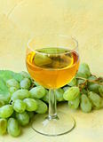 glass of white wine and a branch of green grapes