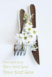 Fork, knife and a small bouquet of white flowers