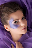beauty shot of a girl with purple glitter make up laying between