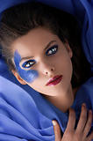 beautiful girl laying between blue satin sheets