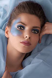 portrait of a model laying between azure sheets