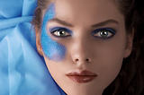 face shot of a laying model with blue glitter make up