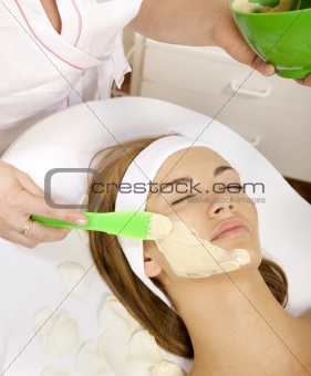 young woman getting beauty skin mask treatment on her face 