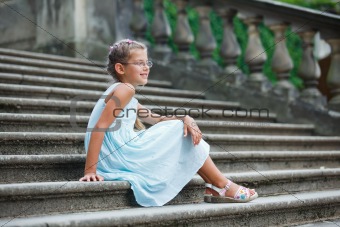 beautiful girl sits on on the stairs in a park
