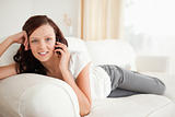 Smiling woman on the phone lying on a sofa