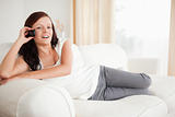Smiling red-haired woman on the phone relaxing on a sofa