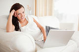 Red-haired woman relaxing on a sofa surfing the internet looking into the camera