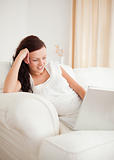 Beautiful red-haired woman relaxing on a sofa surfing the internet