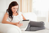 Beautiful woman relaxing on a sofa surfing the internet  with a tablet