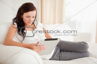 Beautiful woman relaxing on a sofa surfing the internet  with a tablet