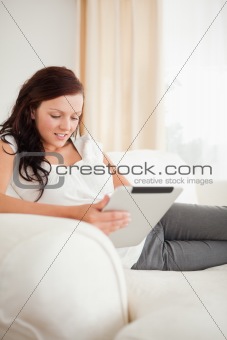 Beautiful red-haired woman relaxing on a sofa with a tablet