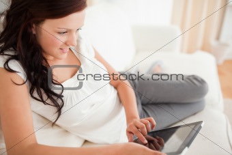 Beautiful red-haired woman lying on a sofa with a tablet