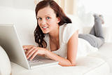 Relaxed red-haired woman searching the internet looking into the camera