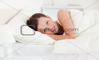 Red-haired woman lying in bed