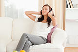 Cute woman relaxing on a sofa listening to music