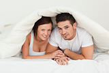 Cherrful couple hiding under a blanket