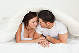 Happy couple hiding under a blanket