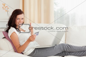 Woman with laptop and credit card holding thumb up
