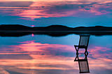 Chair in calm water with sunset