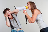 angry woman yelling into a megaphone to another scared girl - isolated on gray