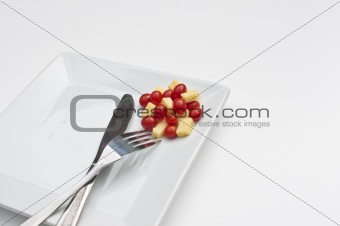 Chese and tomatoes on a plate with a knife and fork