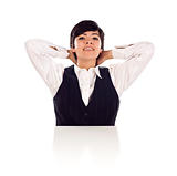Attractive Smiling Mixed Race Young Adult Female Sitting At White Table with Hands Behind Her Head Isolated on a White Background.