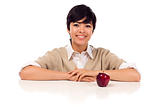 Smiling Mixed Race Young Adult Female Sitting at White Table with Apple Isolated on a White Background.