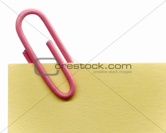 Pink paperclip on a yellow note with white background