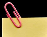 Pink paperclip on a yellow note with white background