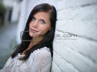 attractive girl leaning on wall and smiling 
