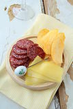 salami, cheese and potato chips, snack on a wooden board