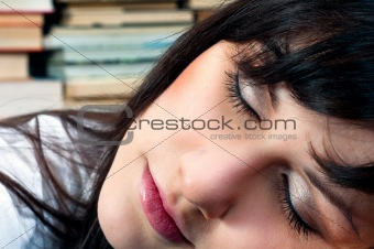 Beautiful young school girl in library sleeping