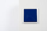 light switch on the wall with blue button on silver frame
