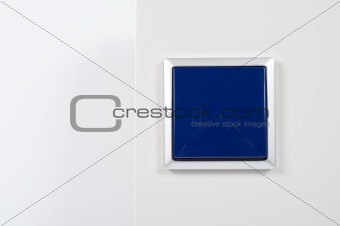 light switch on the wall with blue button on silver frame
