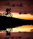 silhouette of mountain biker with Reflection and sunset