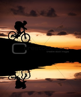 silhouette of mountain biker with Reflection and sunset