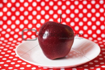 Red juicy apple on a white plate
