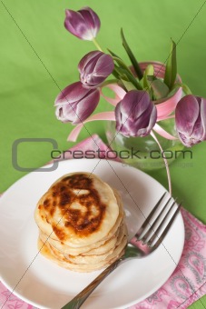 Delicious pancakes for breakfast and a vase with a bouquet of tulips