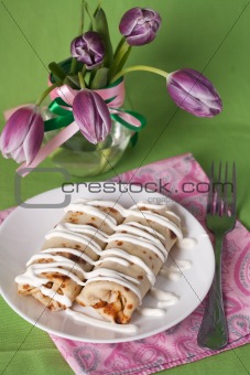 Pancakes with sour cream for breakfast and a vase of purple tulips