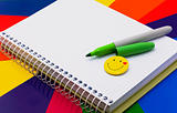 notebook, felt-tip pen of green  badge-smile on colour paper